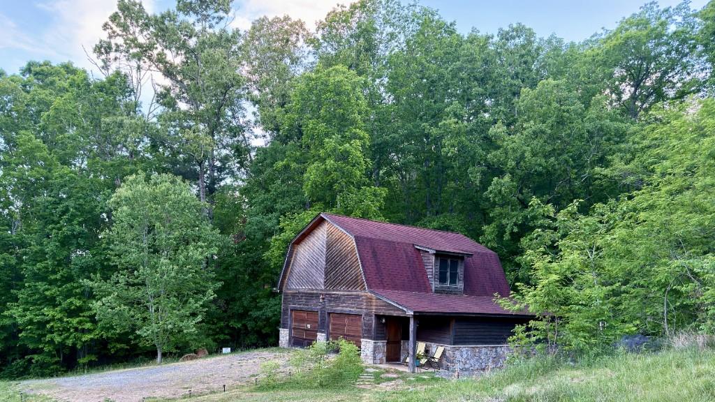 Inspire Barn exterior with gambrel roof, forest backdrop, and driveway